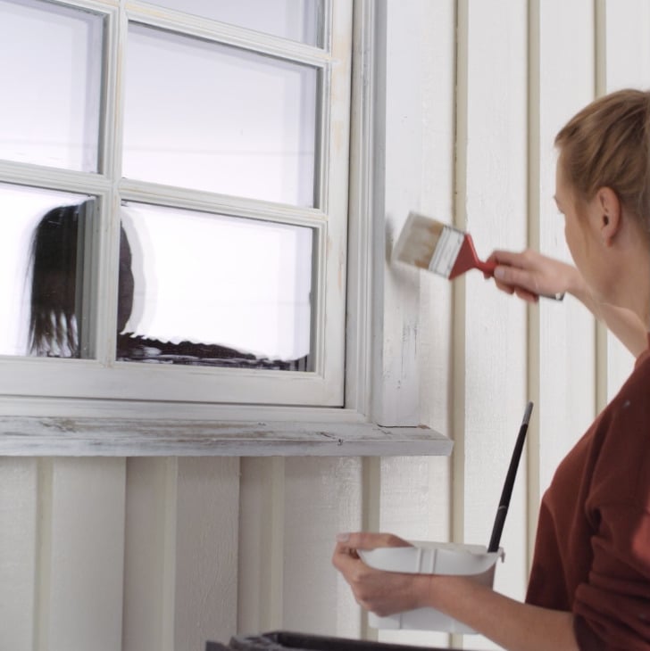 Kvinne maler vindu utendørs