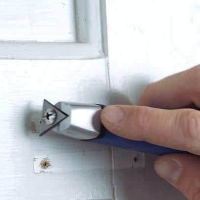 Et skrapeverktøy som skraper av maling på en dør